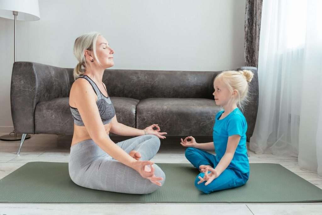 A woman doing yoga with her granddaughter